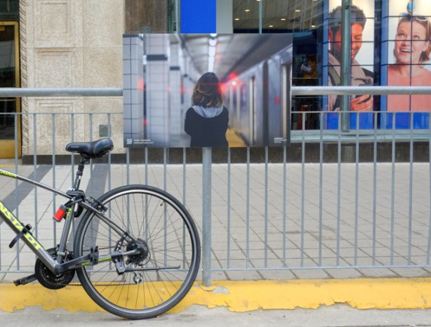 photograph of young woman from behind, mounted on a metal fence to which a bike has been locked