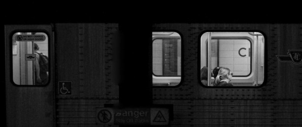 subway stopped at Christie station, one man isgetting off, can be seen through windows, while a woman sits by another window