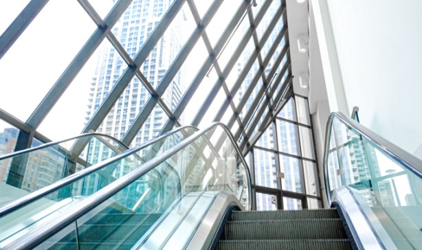 coming to the top of an escalator to an atrium where the walls are glass