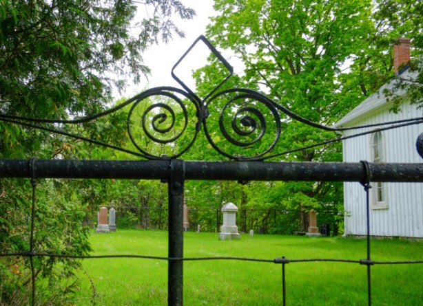 wrought iron details above a metal gate, entrance to churchyard