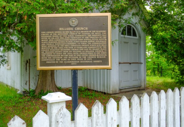 historical society plaque in front of hillside church, white picket fence
