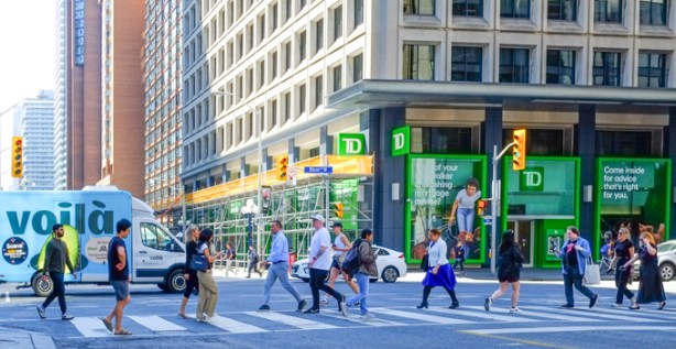Many people crossing Bay street on north side of Bloor. intersection of Bay and Bloor. TD bank on the southwest corner