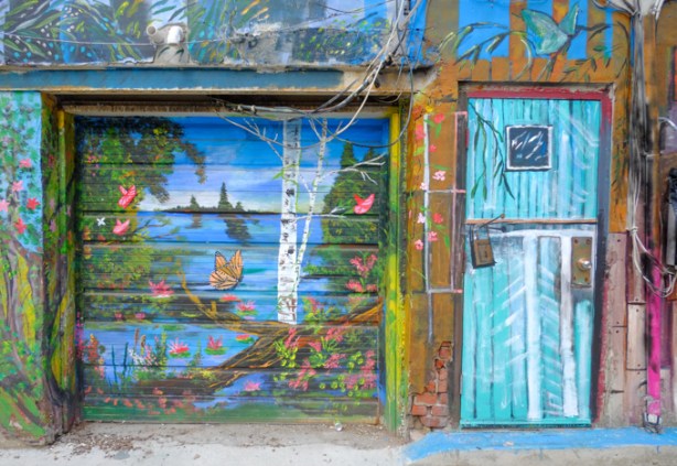 water, stream, nature scene, beside a door painted like bright blue boards, part of a mural by B C Johnson in Gloucester Place 