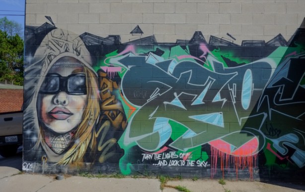 mural in alley,woman wearing sunglasses, text that says