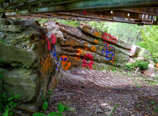 graffiti on rock and concrete under a bridge