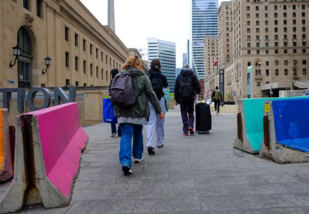 people with suitcases walking towards entrance of Union station, along Front Street