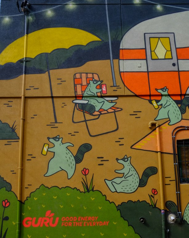 Emily May Rose raccoons go camping, with a grey and orange trailer, a yellow umbrella, and a folding chair too