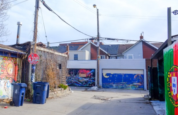 in a laneway with street art murals on all the garage doors