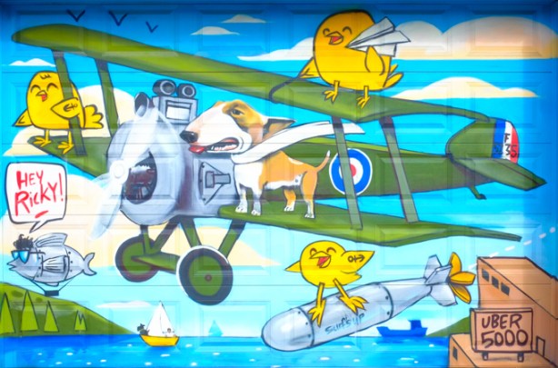 uber 5000 mural, green biplane with 3 yellow birdies, including one standing on a bomb. dog standing on one of the airplane wings
