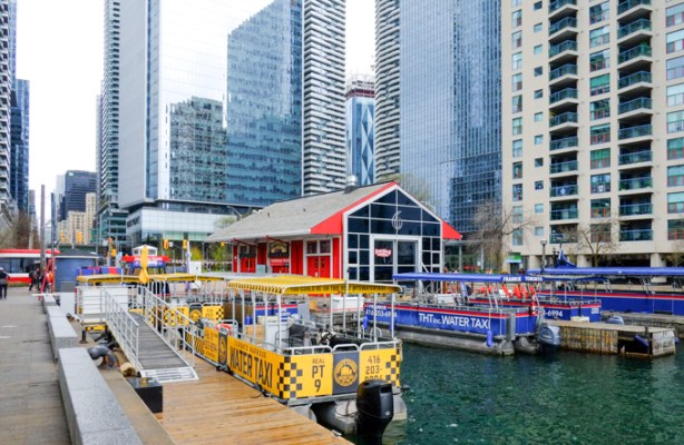 along the waterfront, yellow water taxi for Centre Island, red building for tourist store, downtown skyscrapers