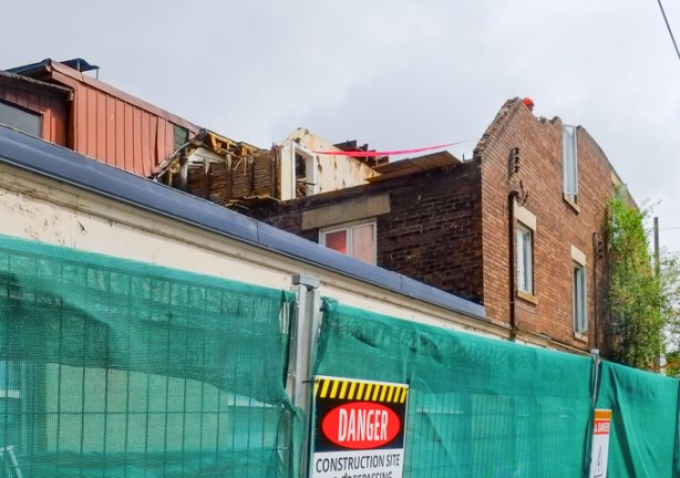 demolition of an old building, behind green hoardings