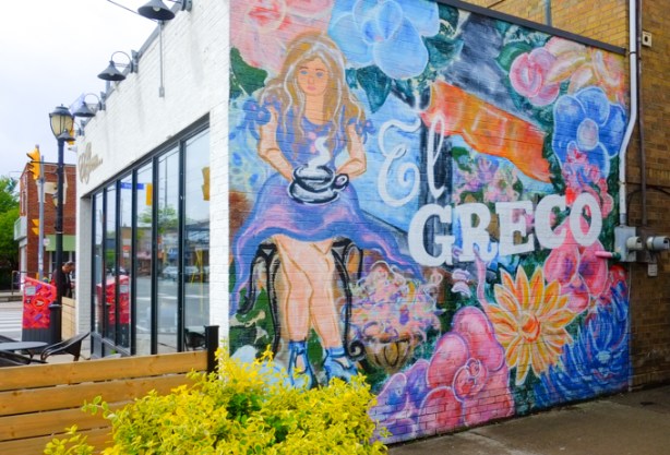 mural on the side of El Greco restaurant, a woman drinking a large mug of coffee
