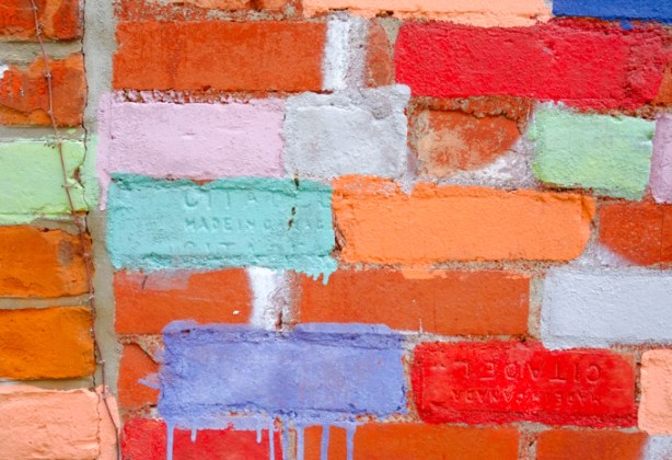 red brick wall where some bricks have been painted different colours. a couple of the bricks have been stamped with the words Citadel Made in Canada