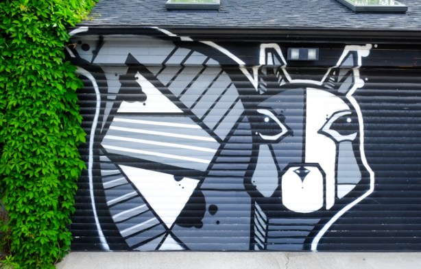 a large squirrel painted on a garage door, lots of straight lines and angles, in shades of black, white, and grey