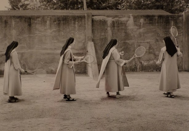 framed black and white photo from convent series by clara gutsche, nuns outside hitting tennis balls with tennis racquets, against a wall