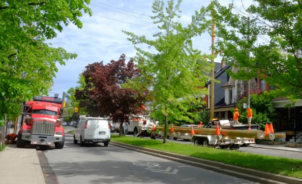 large flatbed truck carrying new utility poles parked on shaw street, workmen 