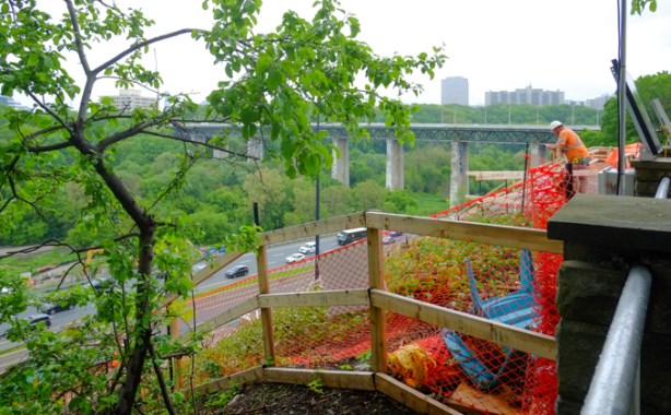 construction site at north end of Pape, on hill overlooking Don Valley Parkway, workman leaning on fence, new entrance to Ontario Line being built here