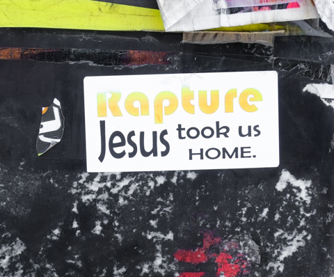 graffiti sticker on a pole that says Rapture Jesus took us home