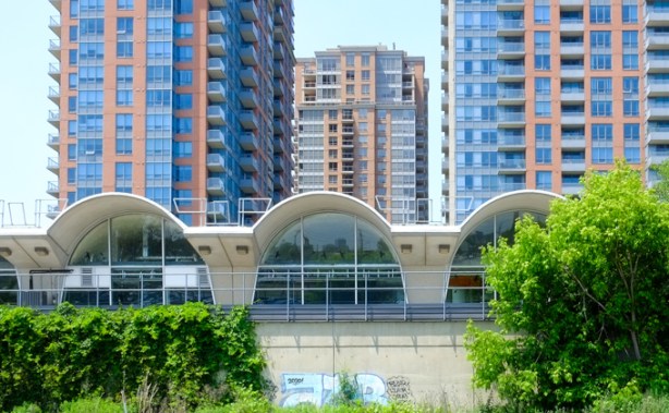 rounded roof of Kipling TTC subway station, semi circles, with three newer condo buildings behind