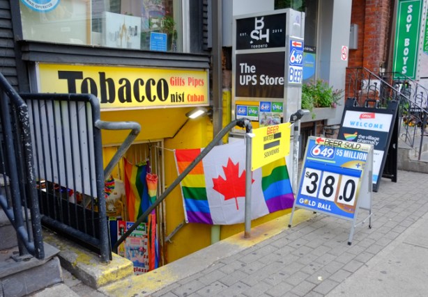 convenience store, lower level, steps down to it, on church street, with rainbow canadian flag, ad of lott max lottery, ups store ad,