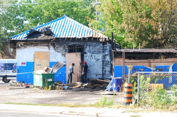 men boarding up burned out gas station