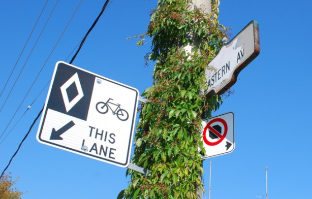 toronto street sign for eastern avenue, on a pole covered with vine and ivy