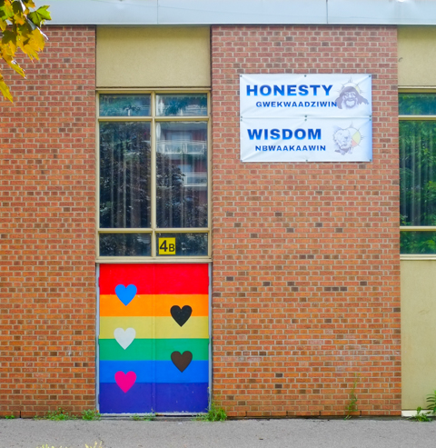 doorway of a school with rainbow stripes and hearts, and some words in indigenous language