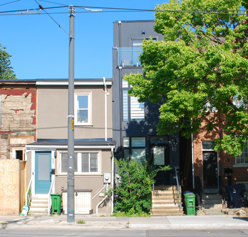 row of houses on leslie street, one has a bright turquoise front door and the one beside it has had a third storey added to it