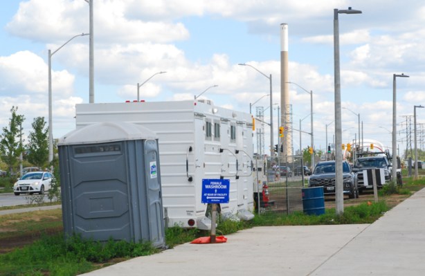 temporary toilet faciities in a portable building, white, by sidewalk, port lands, by biidaasige park