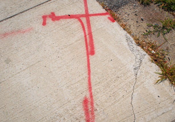 red lines spray painted onto sidewalk, beside a crack in the cement