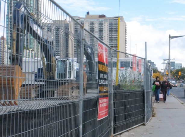 looking east on the north side of St. Clair on Bathurst,, fence around a construction site 