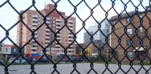 vacant lot behind black chain link fence