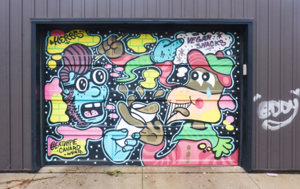 mural on a garage door in an alley, cartoonish characters