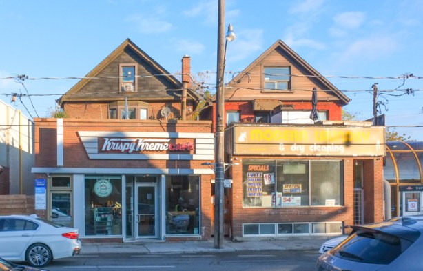 peaks of original houses can be seen over the top of the boxy additions to the structure to make space for stores, krispy kreme donuts on one side, a dry cleaners on the other