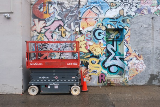 lift parked beside wall covered with street art