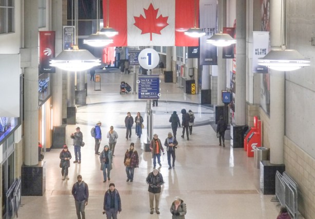 large Canadian flag, and many people walking, inside Scotiabank arena foyer area between arena and Union station