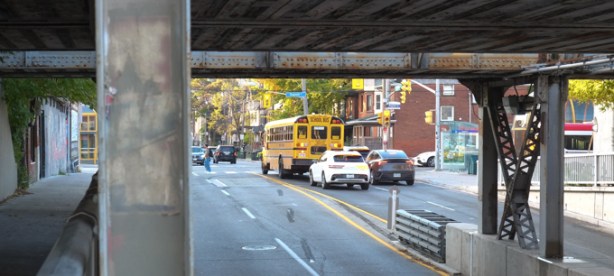 looking through railway underpass, traffic including school bus is stopped at a red light at dupont