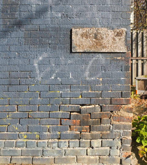 faded blue paint on old brick wall, some bricks cracking and crumbling