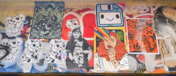 paper pasteup graffiti in graffiti alley, including a blue floppy disc with text that says save me, by catchoo