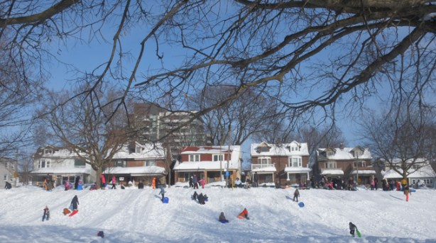 people with sleds and inner tubes and other sliding devices on snow covered hill at East Lynn Park, adults and kids