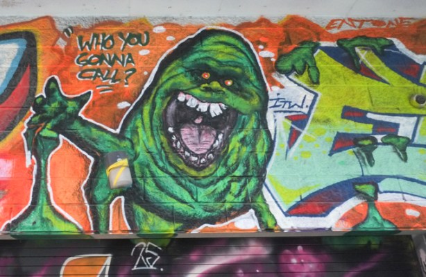 street art mural in graffiti alley with green slime creature from Ghostbusters movie in center