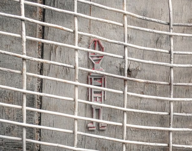white stikman graffiti on a white wall behind metal bars