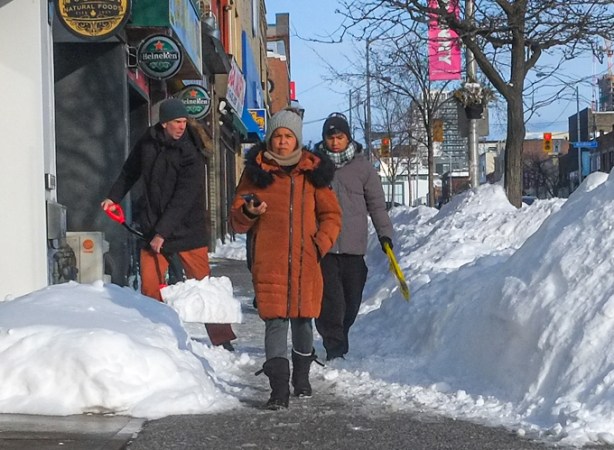 man shoveling snow as people walk past, Danforth