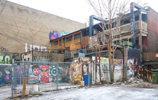 parking areas and back yards of stores on Queen street, graffiti alley view, three storeys, with balconies across the back street art and graffiti on fences