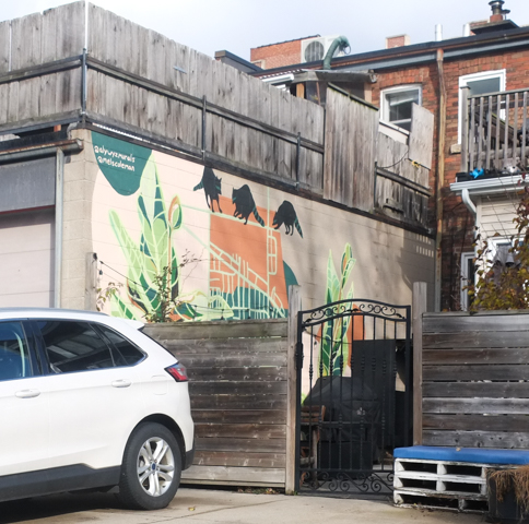 mural in a backyard by alywyz murals, black raccoons on top of a house, with window, greenery beside the house,