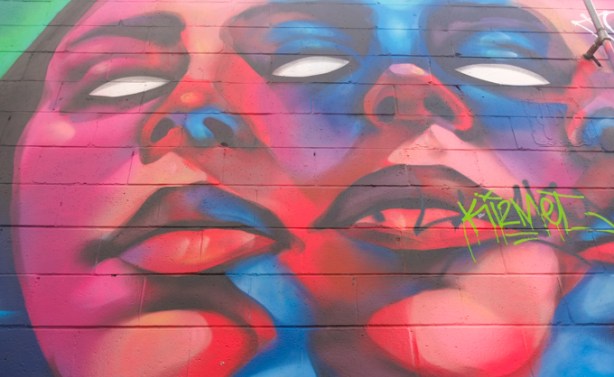 street art mural by kizmet, red faces with white eyes, some blue highlights, 2 faces, very large