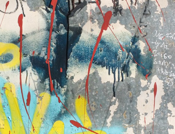 close up of spray paint and splotchy graffiti in many colours on an old metal garage door