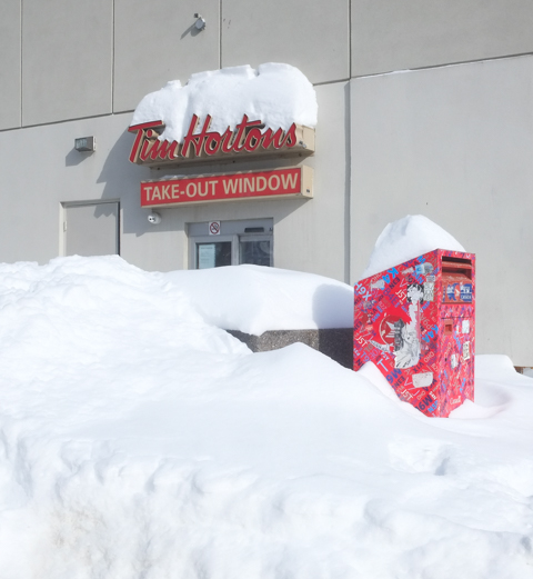 snow bank in front of Tim Hortons take out window, also a Canada Post mailbox in the snow