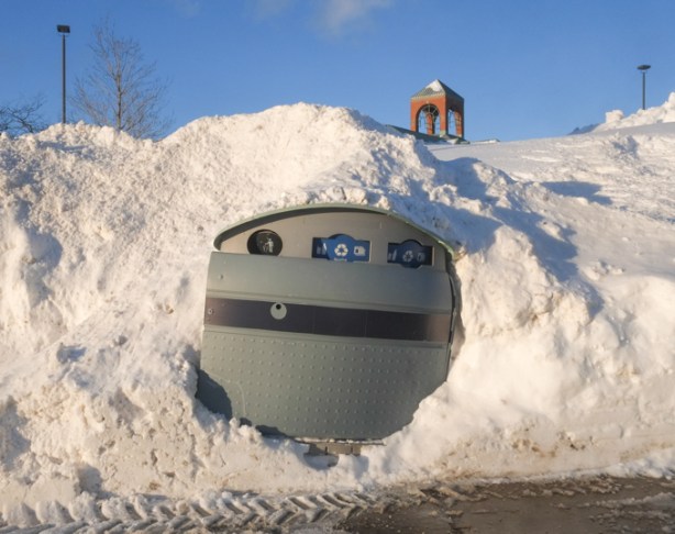 sidewalk plastic garbage bin in a snow bank