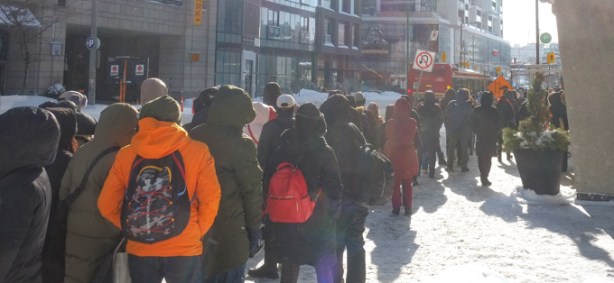 winter day, people on sidewalk waiting for TTC shuttle bus on Yonge Street, cold, snowing, hats and scarves